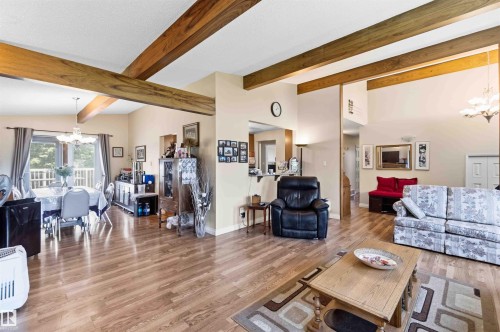 Vaulted ceilings with exposed wood beams define this open concept living area featuring wood-finish flooring - 13121 122 Street, Edmonton, AB 