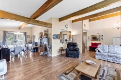 Vaulted ceilings with exposed wood beams define this open concept living area featuring wood-finish flooring - 