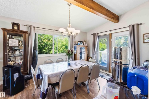 Dining area featuring vaulted ceilings with exposed wood beams, wood-finish flooring, and a chandelier light fixture - 13121 122 Street, Edmonton, AB 