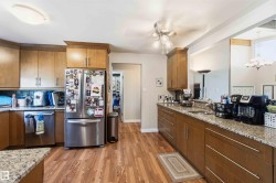 Kitchen featuring wood-finish flooring, light wood cabinetry, stone-finish countertops, and a tile backsplash - 