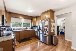 Kitchen featuring wood cabinetry, granite-look countertops, stainless steel appliances, and wood-finish flooring - 