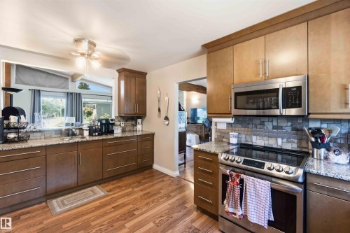 Kitchen featuring wood-finish flooring, granite countertops, and a tiled backsplash - 13121 122 Street, Edmonton, AB 