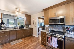 Kitchen featuring wood-finish flooring, granite countertops, and a tiled backsplash - 