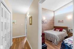 Bedroom with wood-finish flooring, a feature wall with horizontal paneling, and an upper transom window - 