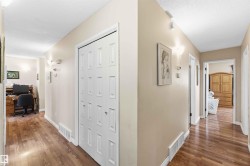 Hallway featuring wood-finish flooring, neutral wall paint, and white bi-fold doors - 