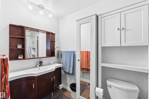 Bathroom featuring a dark wood vanity with an integrated white sink, a wall-mounted mirrored cabinet with open shelving, and track lighting - 13121 122 Street, Edmonton, AB 