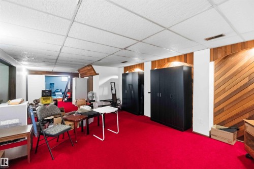 Room featuring red carpeting, wood-paneled accents, and a drop ceiling - 13121 122 Street, Edmonton, AB 