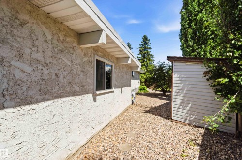 Exterior featuring textured stucco siding, a white soffit, and a window with white trim - 13121 122 Street, Edmonton, AB 