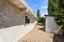 Exterior featuring textured stucco siding, a white soffit, and a window with white trim - 