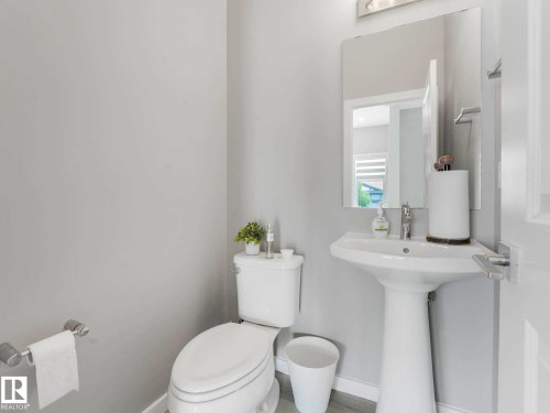 Pedestal sink with chrome faucet, complemented by a rectangular mirror and an overhead light fixture - 516 35 Street, Edmonton, AB 