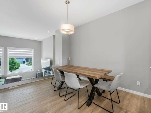 Dining area featuring wood-finish flooring, two large windows with blinds, a contemporary drum pendant light, and recessed ceiling lighting - 516 35 Street, Edmonton, AB 
