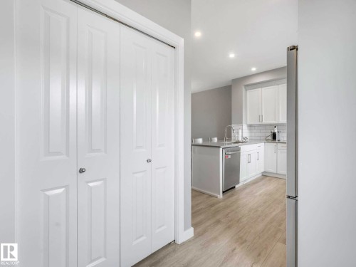 Bright kitchen featuring white cabinetry, subway tile backsplash, stainless steel dishwasher, and light wood-finish flooring - 516 35 Street, Edmonton, AB 