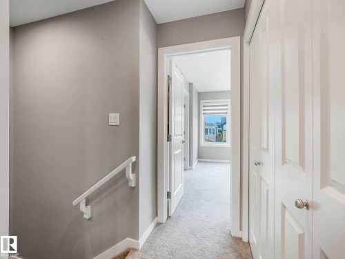 Carpeted hallway featuring light gray walls, white trim, and a white handrail - 516 35 Street, Edmonton, AB 