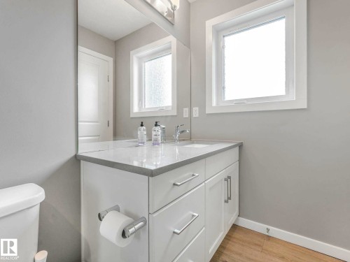 Bathroom vanity featuring a light-toned countertop, integrated sink, and white cabinetry with chrome hardware - 516 35 Street, Edmonton, AB 