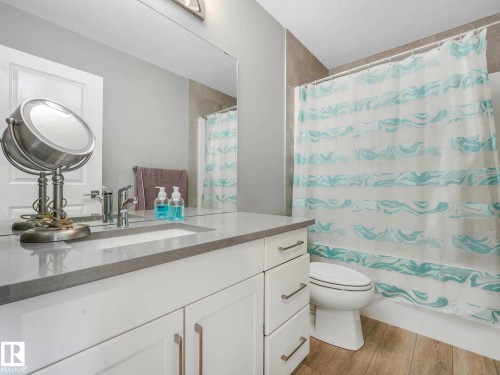Bathroom featuring a white vanity with an integrated sink and light gray countertop, complemented by a large mirror and modern vanity lighting - 516 35 Street, Edmonton, AB 