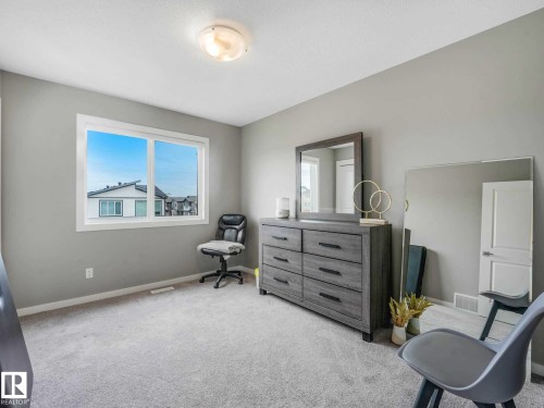 Carpeted room featuring light gray walls, a window with white trim, and a flush mount ceiling light fixture - 516 35 Street, Edmonton, AB 