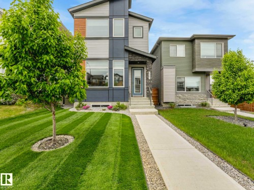 Contemporary facade featuring a multi-tone exterior, large windows, stone accents, and a covered entryway - 516 35 Street, Edmonton, AB 