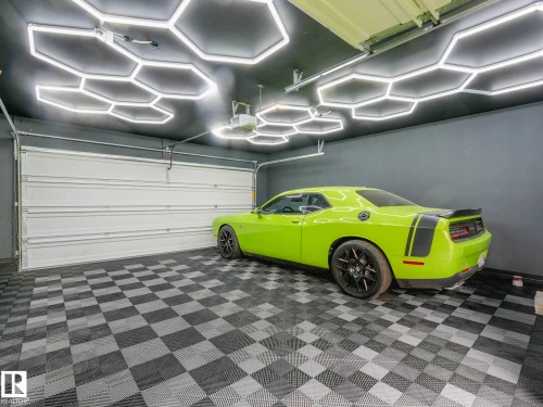 Garage featuring hexagonal ceiling lighting, gray walls, a white sectional garage door, and checkerboard floor tiling - 516 35 Street, Edmonton, AB 