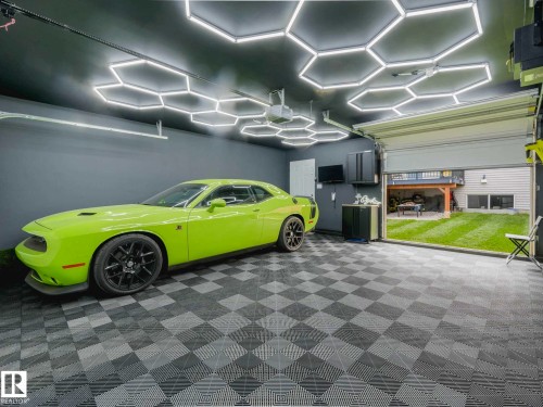 Garage featuring geometric ceiling lighting, checkerboard floor tiling, and a roll-up door - 516 35 Street, Edmonton, AB 