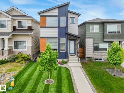 Modern two-story home featuring a contemporary facade with contrasting grey and blue siding, complemented by wood-look panel accents - 516 35 Street, Edmonton, AB 