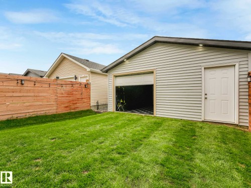 Detached garage structure featuring light-colored siding, an overhead door, and a side entry door - 516 35 Street, Edmonton, AB 