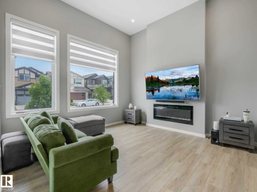 Living area featuring light wood-finish flooring, recessed lighting, and a wall-mounted electric fireplace - 516 35 Street, Edmonton, AB 