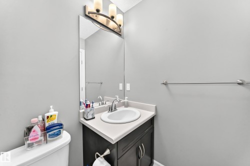 Compact bathroom featuring a single vanity with a white countertop and dark wood-finish cabinetry, under-mount sink, and chrome faucet - 10-415 Clareview Rd Nw Nw, Edmonton, AB 