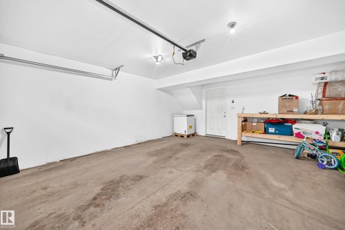 Spacious garage featuring a concrete floor, bright white walls, overhead lighting, and an automatic garage door opener - 10-415 Clareview Rd Nw Nw, Edmonton, AB 