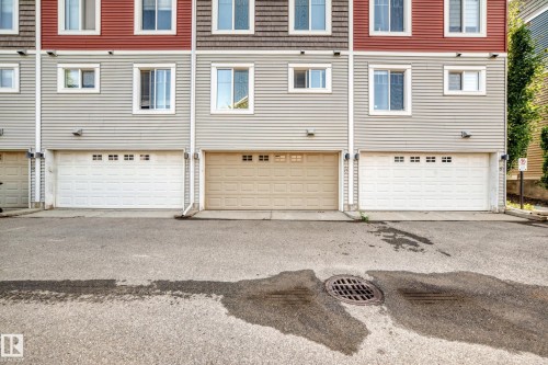 Multi-level townhome exterior featuring an attached garage with a panel door and upper window inserts - 10-415 Clareview Rd Nw Nw, Edmonton, AB 