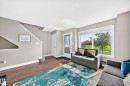 Spacious living area featuring wood-finish flooring, light gray wall paint, and white trim - 10-415 Clareview Rd Nw Nw, Edmonton, AB 
