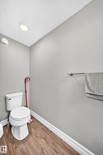 Powder room featuring light gray walls, wood-finish flooring, recessed lighting, and a white toilet - 10-415 Clareview Rd Nw Nw, Edmonton, AB 