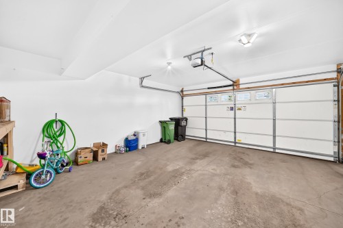 Spacious two-car garage featuring a concrete floor, white painted walls, and an automatic overhead door opener - 10-415 Clareview Rd Nw Nw, Edmonton, AB 
