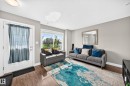 Living area featuring wood-finish flooring, neutral wall tones, and a large window providing ample natural light - 10-415 Clareview Rd Nw Nw, Edmonton, AB 