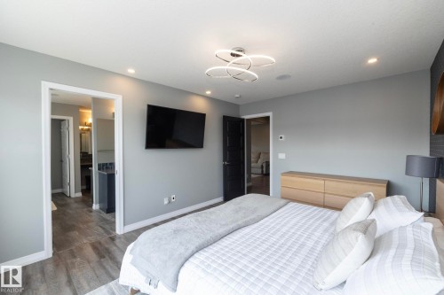 Spacious bedroom featuring wood-finish flooring, recessed lighting, and a contemporary ceiling fixture - 923 Mcconachie Boulevard, Edmonton, AB 