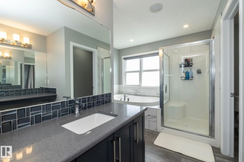 Bathroom featuring a grey countertop vanity with an integrated sink, a tiled backsplash, and a large mirror - 923 Mcconachie Boulevard, Edmonton, AB 