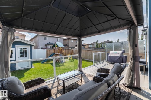 Covered outdoor patio area featuring a composite deck and glass panel railing - 923 Mcconachie Boulevard, Edmonton, AB 