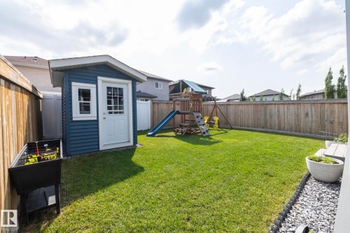 Expansive backyard featuring a manicured lawn, full privacy fencing, and a dedicated storage shed with blue siding - 923 Mcconachie Boulevard, Edmonton, AB 