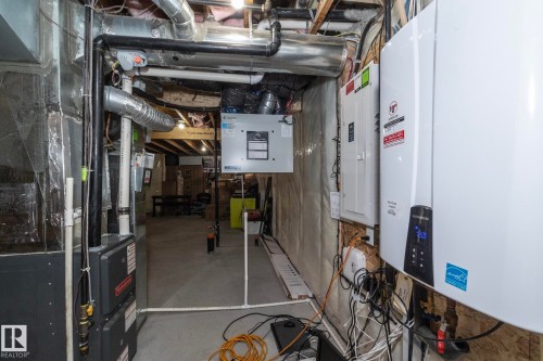 Utility area featuring a tankless water heater, electrical panels, and exposed ductwork - 923 Mcconachie Boulevard, Edmonton, AB 