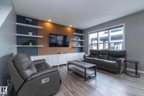 Living room featuring wood-finish flooring and a large picture window - 923 Mcconachie Boulevard, Edmonton, AB 