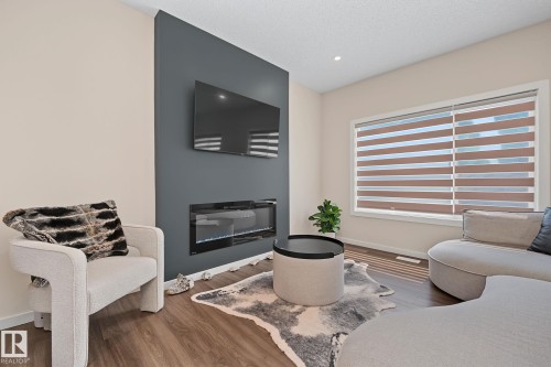 Living area featuring a floor-to-ceiling accent wall with an inset electric fireplace - 432 Roberts Crescent, Leduc, AB 