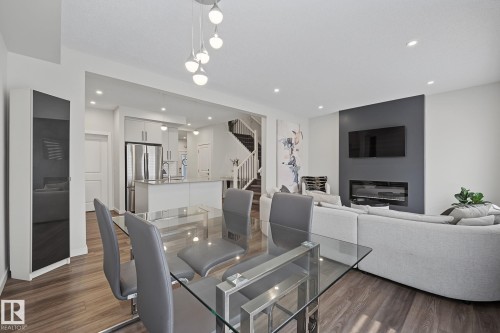 Open-concept living space featuring wood-finish flooring, recessed lighting, and a modern linear fireplace - 432 Roberts Crescent, Leduc, AB 