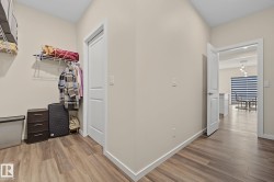 Hallway featuring wood-finish flooring, light neutral paint, and white baseboards - 