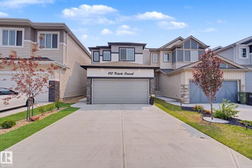 Modern two-story residence featuring a paved driveway, integrated garage, and stone facade accents - 432 Roberts Crescent, Leduc, AB 