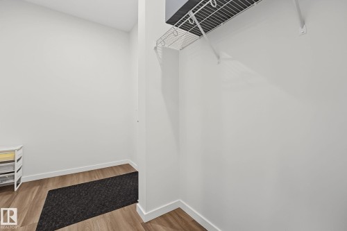 Compact storage area featuring wood-finish flooring, white walls, and a white wire shelf with a hanging rod - 432 Roberts Crescent, Leduc, AB 