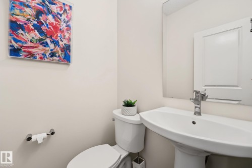 Pedestal sink with chrome faucet, toilet, and wall-mounted mirror - 432 Roberts Crescent, Leduc, AB 