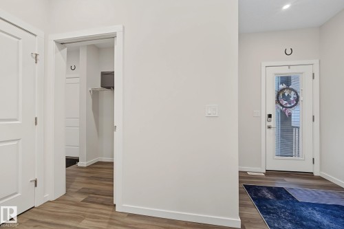 Foyer with wood-finish flooring, white trim, and light-colored walls - 432 Roberts Crescent, Leduc, AB 