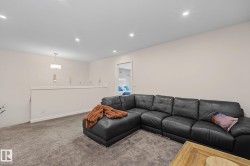 Carpeted entertainment area featuring recessed lighting, a neutral wall color, and a half-wall partition with a modern pendant light fixture - 