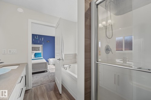 Bathroom featuring a glass-enclosed shower, built-in bathtub, and a vanity with a light countertop - 432 Roberts Crescent, Leduc, AB 