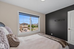 Bedroom featuring a large multi-pane window, dark accent wall, ceiling-mounted light fixture, and white interior door with brushed nickel hardware - 