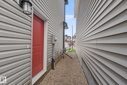 Red entry door with an overhead lantern fixture - 432 Roberts Crescent, Leduc, AB 